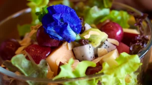 Video von lila Blüten auf frischem Gemüse und Obstsalat — Stockvideo