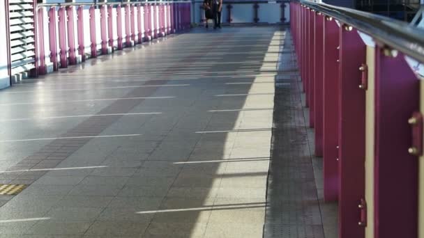 Пассажиры, люди, идущие по мосту на вокзале с перилами и солнечным светом. абстрактный транспорт — стоковое видео