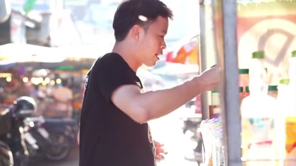 タイのローカル市場でドリンクを買う男性のビデオ — ストック動画
