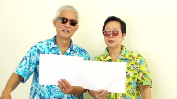 Video Happy Asian senior couple holding white blank sign ready for holiday trip — Stock Video