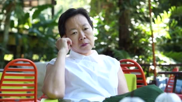 亚洲高级女性思想和担心在郁郁葱葱的绿色自然背景 — 图库视频影像