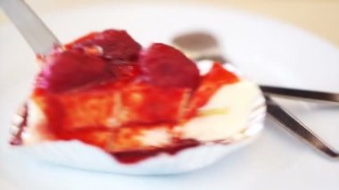Yemek ve beyaz kabarık çilekli cheesecake kesme