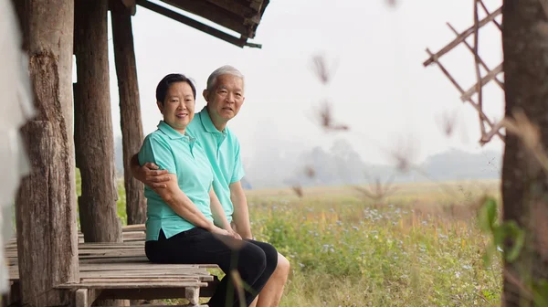 Asiatisches Seniorenpaar sitzt im Pavillon neben Reisfeld — Stockfoto