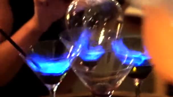 Gieten en drinken alcohol cocktail flamberen. blauwe ontslagen cocktailglas tier — Stockvideo