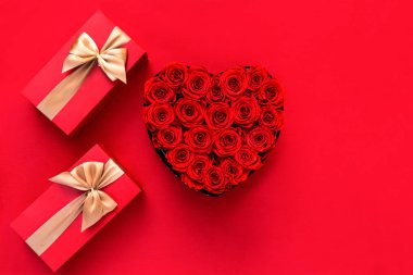 Noel hediyesi ve çiçek dekoru olan kırmızı bir arka plan. Kopyalama alanı olan üst görünüm. Minimalizm. Mutlu Noeller..