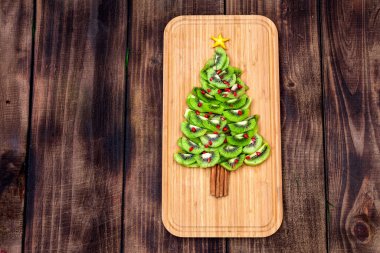 Kivi Noel ağacı. Çocukların partisi ya da kahvaltısı için eğlenceli yemek fikri. Tahta arka planda yeni yıl yemeği. Noel ağacı yiyeceği konsepti. Düz yatıyordu. Üst görünüm.