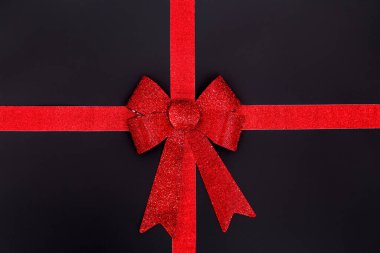 Sevgililer Günü hediyesi, siyah arka planda izole edilmiş kırmızı bir fiyonk. Kırmızı pruva. Sevgililer Günü kartı konsepti.