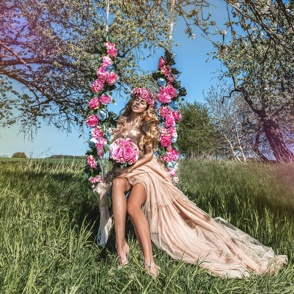 春のファッション 花のスイングに魅力的なブロンドの美しさ 春のコンセプト エレガントなピンクの美しい自然女性は 花のスイングにパステルドレス ウェディングファッションと花嫁のコンセプト — ストック写真