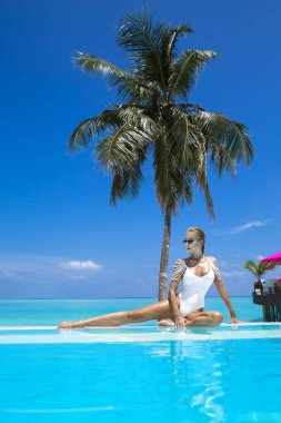 Güneş yanığı ince ve düzgün vücutlu beyaz bikinili zarif seksi kadın Maldivler adasındaki yüzme havuzunun yanında poz veriyor. Maldivler 'de lüks bir tatil köyünde mükemmel bir vücut bikini modeli. Lüks seyahat.