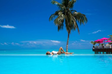 Güneş yanığı ince ve düzgün vücutlu beyaz bikinili zarif seksi kadın Maldivler adasındaki yüzme havuzunun yanında poz veriyor. Maldivler 'de lüks bir tatil köyünde mükemmel bir vücut bikini modeli. Lüks seyahat.
