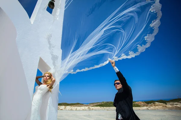 La hermosa pareja joven en santorini en un vestido de novia con el pez de colores de cola larga — Foto de Stock