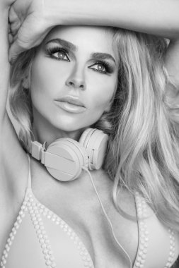 Portrait of a very beautiful blond hair woman in sexy outfit with headphones around his neck in a wondrous makeup