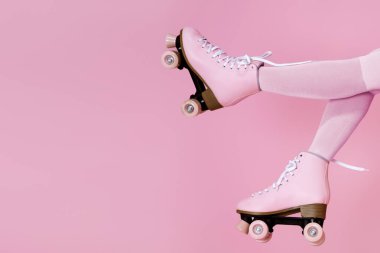 Pembe arka plan üzerinde kadın bacakları üzerinde pembeleşen patenler