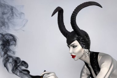 Kara boynuzlu ve kırmızı dudaklı kara kraliçe dramatik cadılar bayramı portresi içinde duman fantezisi olan cadı ve kötü adam görünüşü