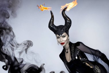 Kara boynuzlu ve kırmızı dudaklı kara kraliçe dramatik cadılar bayramı portresi içinde duman fantezisi olan cadı ve kötü adam görünüşü