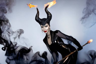 Kara boynuzlu ve kırmızı dudaklı kara kraliçe dramatik cadılar bayramı portresi içinde duman fantezisi olan cadı ve kötü adam görünüşü