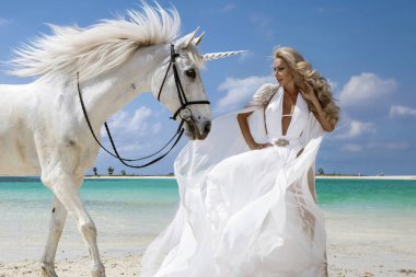 Beyaz elbisesi ve kristal tacı olan zarif bir kadın Mauritius 'da tropik bir plajda görkemli beyaz bir atla birlikte egzotik bir cennette duruyor.