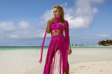 Güneşli bir yaz gününde Mauritius plajında pembe makrome elbise ve kuş tüyü taç giymiş çekici bir manken poz verir. Yaz modası.