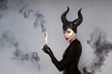 Kara boynuzlu ve kırmızı dudaklı kara kraliçe dramatik cadılar bayramı portresi içinde duman fantezisi olan cadı ve kötü adam görünüşü
