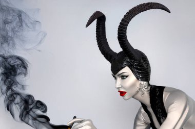 Kara boynuzlu ve kırmızı dudaklı kara kraliçe dramatik cadılar bayramı portresi içinde duman fantezisi olan cadı ve kötü adam görünüşü