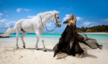 Akan Siyah Elbiseli Zarif Kadın ve Altın Korse Pozisyonu Görkemli Beyaz At Mauritius 'ta Turkuaz Suyu ve Palmiye ağaçlarıyla tropik bir plajda