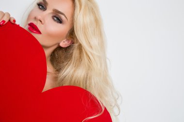 Güzel sarışın seksi kadın modeli kız aşık onun yüz ve kırmızı dudaklar ve kırmızı Erotik çamaşır uzun bacakları çıplak kırmızı büyük bir kalbi olan Sevgililer günü