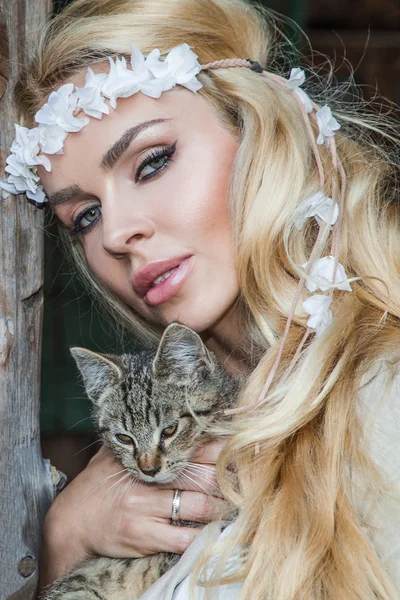 Mooie blonde vrouw met lang haar vrij sexy ogen en mond op het wilde westen met een zoete grijze kitten op handen — Stockfoto