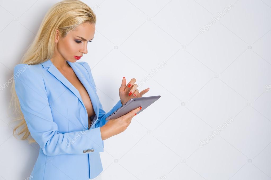 Beautiful young sexy blond woman girl businesswoman secretary in the elegant light blue jacket, suit the makeup red lipstick, she works, plays, learns, touch tablet and phone