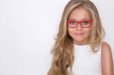 Kameranın resmi beyaz arka plan şaşırtıcı gözleri için bir güzel küçük kız kızı uzun sarı saçlı ve beyaz elbise ve beyaz noktalı kırmızı gözlük portresi bakar