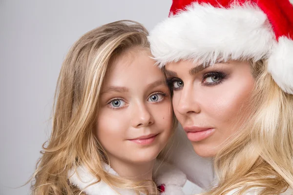 Preciosa madre rubia sexy con una hija niña vestida como Santa Claus abrazo en Navidad en el invierno y la nieve —  Fotos de Stock