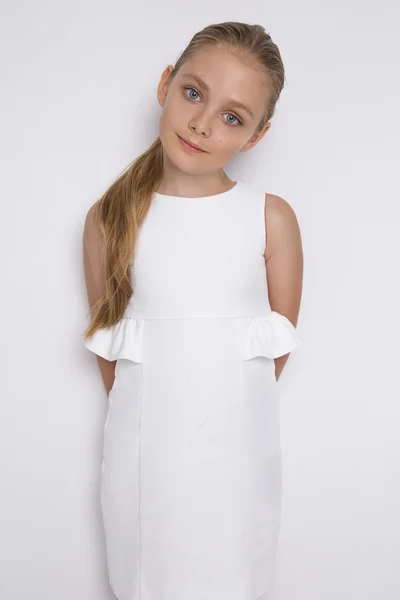 Retrato de una encantadora hija niña en pelo largo y rubio y vestido blanco mira a la cámara, foto sobre el fondo blanco ojos increíbles — Foto de Stock