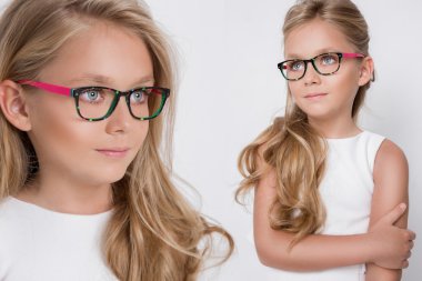 Kameranın resmi beyaz arka plan şaşırtıcı gözleri için bir güzel küçük kız kızı uzun sarı saçlı ve beyaz elbise ve beyaz noktalı kırmızı gözlük portresi bakar