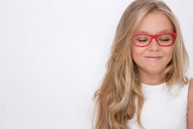 Kameranın resmi beyaz arka plan şaşırtıcı gözleri için bir güzel küçük kız kızı uzun sarı saçlı ve beyaz elbise ve beyaz noktalı kırmızı gözlük portresi bakar