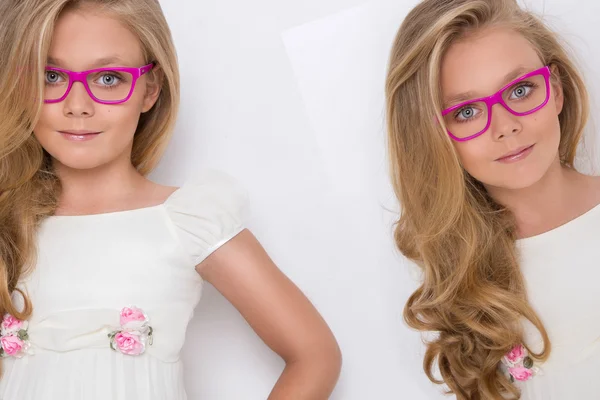 Portrait of a lovely little girl daughter in long blond hair and white dress and red glasses with white dots looks at the camera, photo on the white background amazing eyes — Stock Photo, Image