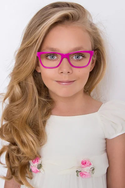 Retrato de una encantadora hija niña en pelo largo y rubio y vestido blanco y gafas rojas con puntos blancos mira a la cámara, foto sobre el fondo blanco ojos increíbles —  Fotos de Stock