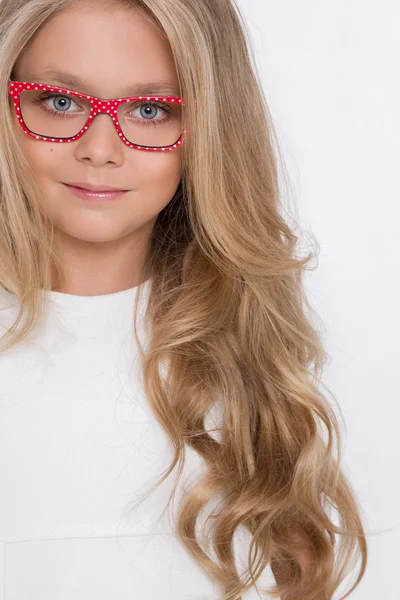 Portrét krásné holčička dcery v dlouhé blond vlasy a bílé šaty a červené brýle s bílými tečkami se dívá na kamery, Foto na úžasné oči bílé pozadí — Stock fotografie