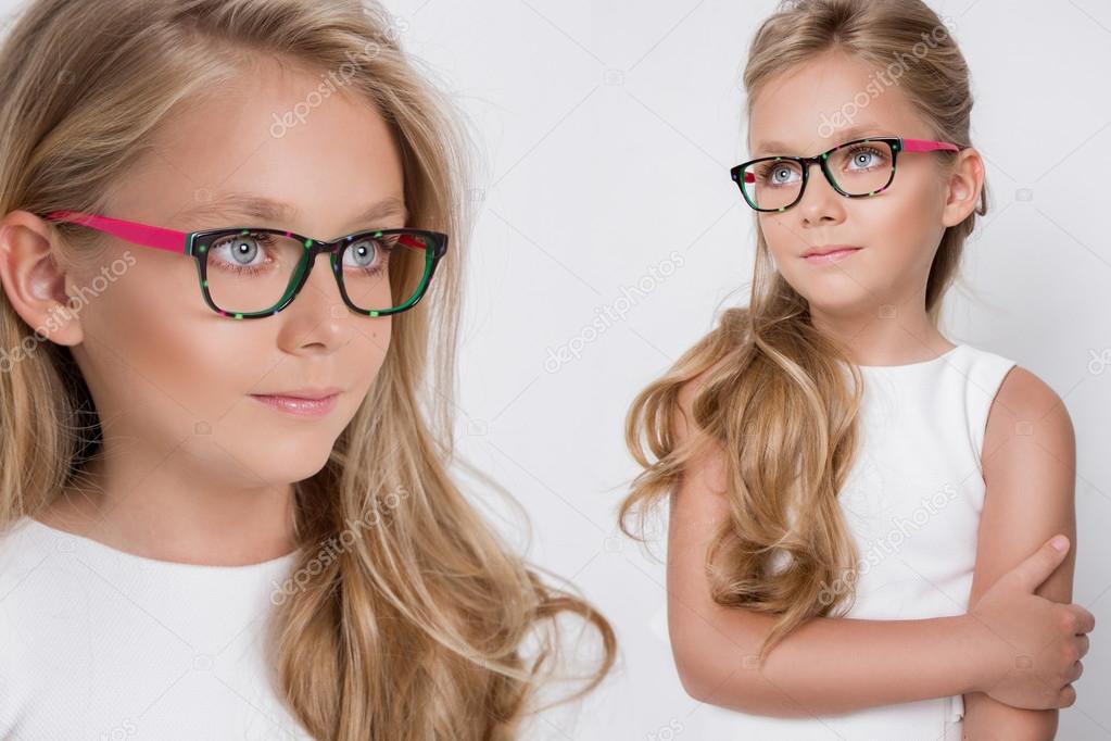 Portrait of a lovely little girl daughter in long blond hair and white dress and red glasses with white dots looks at the camera, photo on the white background amazing eyes