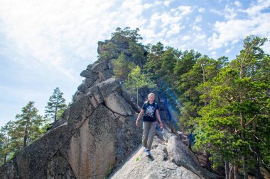 Sırt çantalı ve dağda yürüyüş direkleri olan genç bir kadın.