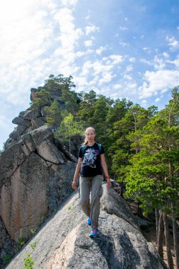 Sırt çantalı genç bir kadın dağda yürüyüş yapıyor.