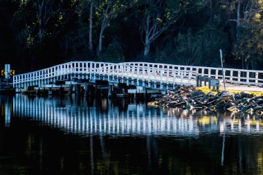 Sabahları sakin gölün karanlık sularına yansıyan beyaz tahta köprü.