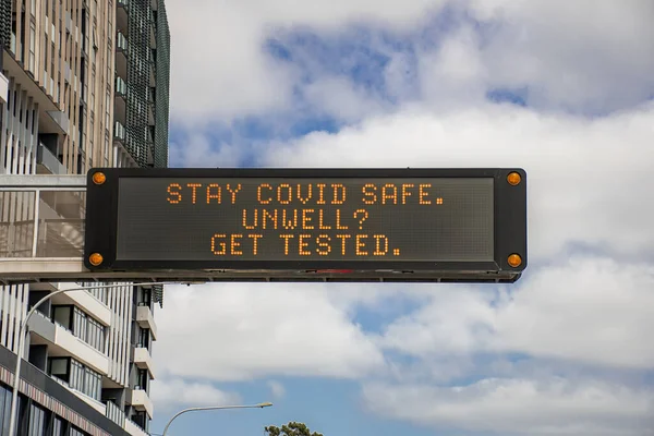 Changeable electronic dynamic road sign reads: -Stay COVID safe. Unwell. Get tested- on the city road. Coronavirus alert