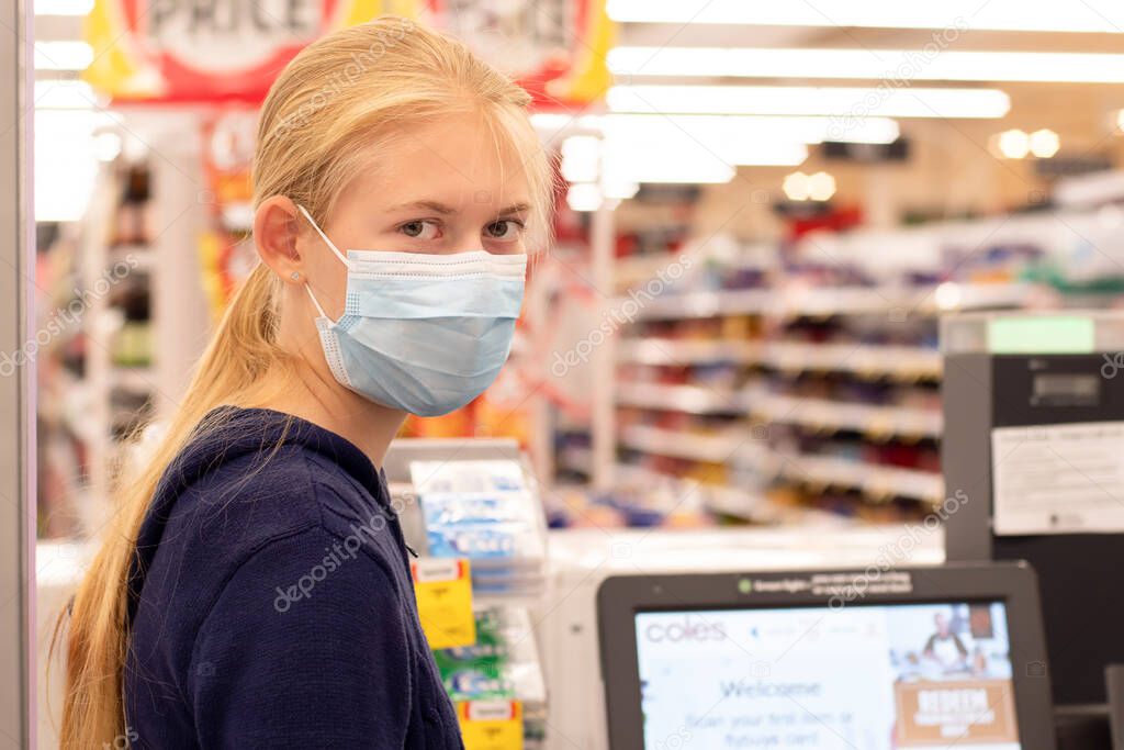 Sydney, Australia - 2020-01-04 Face masks in shopping centres are compulsory in Greater Sydney NSW. A girl wearing disposable face mask at self checkout in Coles supermarket. Covid-19 restrictions