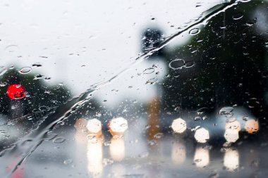 Ön camdan sağanak yağmurun bulanık görüntüsü. Farları olan arabalar ıslak yolda çok az görülür. Sydney sel baskını uyarısı.