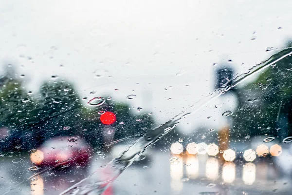 Ön camdan sağanak yağmurun bulanık görüntüsü. Farları olan arabalar ıslak yolda çok az görülür. Sydney sel baskını uyarısı.