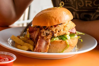 Pastırmalı, peynirli, biftekli lezzetli burger. Marul ve patates kızartması. Kafenin masasının üstünde. Fast food.