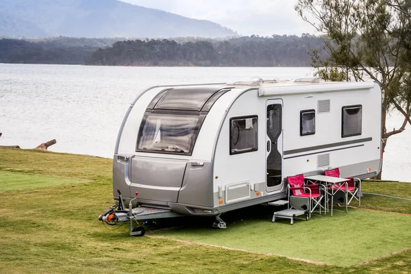 RV caravan camping at the caravan park on a peaceful lake with mountains on the horizon. Camping vacation family travel concept