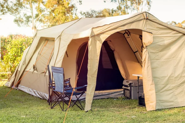 Avustralya 'daki karavan tatil parkındaki kamp alanında sandalyeler, masa ve kamp buzdolabı olan geniş bir çadır.