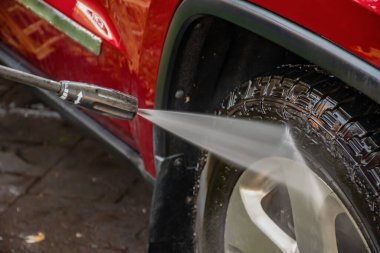 Kırmızı bir SUV 'u yüksek basınçlı çamaşır makinesiyle yıkamak..