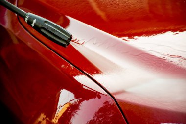 Kırmızı bir SUV 'u yüksek basınçlı çamaşır makinesiyle yıkamak..