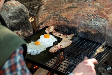 Kahvaltı kampı yemeği. Kamp ateşinin üzerinde ızgara domuz pastırması ve yumurta. Kamp yaşam tarzı